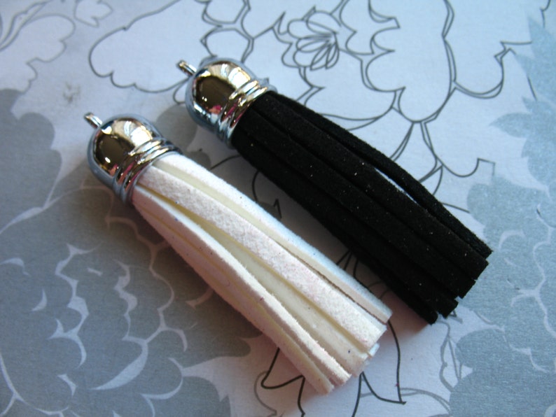 May include: Two tassels, one black and one white, with silver metal tops. The tassels are made of a soft, fuzzy material.