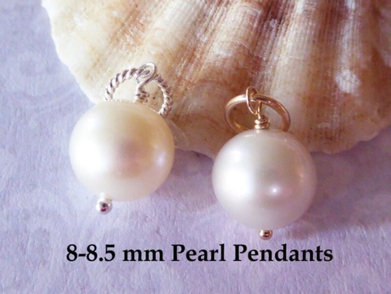 May include: Two white pearl pendants, one with a silver bail and one with a gold bail. The pearls are 8-8.5 mm in diameter. 8-8.5 mm Pearl Pendants