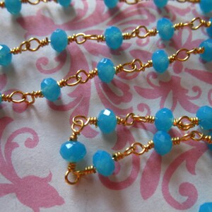 May include: A gold chain necklace with light blue gemstone beads. The chain is made of small, linked gold wire.
