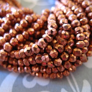 May include: A strand of copper-colored faceted beads. The beads are small and have a metallic sheen.