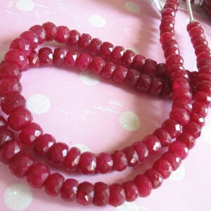 Puede incluir: Una hebra de cuentas de piedras preciosas facetadas de color rojo intenso. Las cuentas est&aacute;n enhebradas en un hilo transparente y est&aacute;n dispuestas en un patr&oacute;n circular.