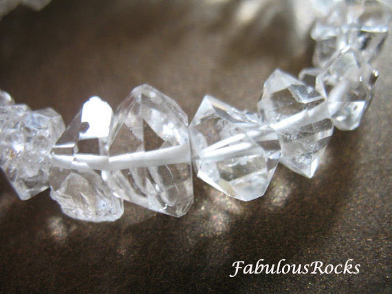 May include: A bracelet made of clear quartz crystals, each crystal is faceted and has a geometric shape. The bracelet is made of many crystals that are strung together.