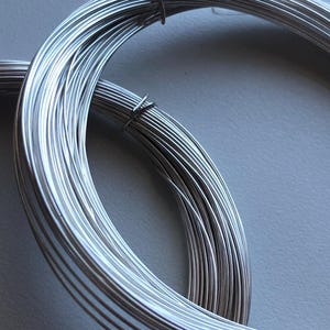Puede incluir: Un rollo de alambre de plata, perfecto para la elaboración de joyas o proyectos de artesanía.