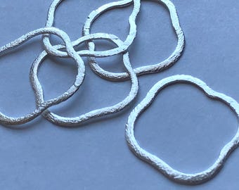 May include: Five silver rings with a textured, wavy surface. The rings are interlocked and create a decorative pattern.