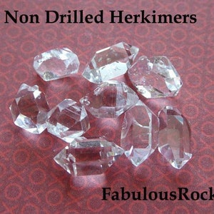 May include: A collection of eight clear, undrilled Herkimer diamonds on a red patterned surface. The text "Non Drilled Herkimers" and "FabulousRocks" are visible in the image.