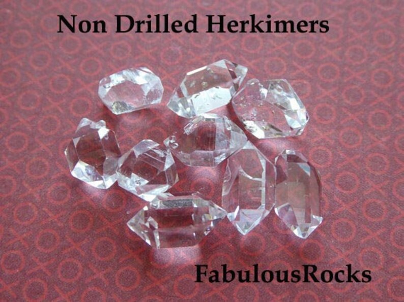 May include: A collection of eight clear, undrilled Herkimer diamonds on a red patterned surface. The text "Non Drilled Herkimers" and "FabulousRocks" are visible in the image.