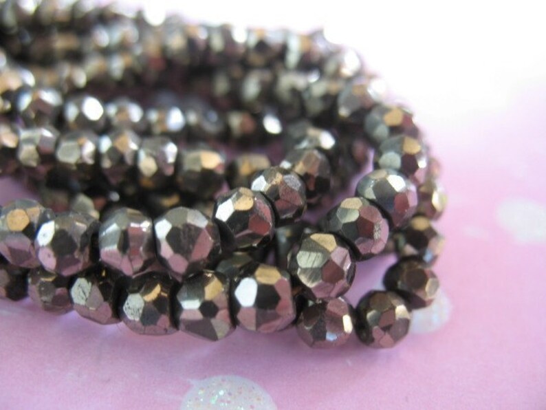 May include: A strand of silver-toned faceted glass beads. The beads are small and have a metallic sheen.