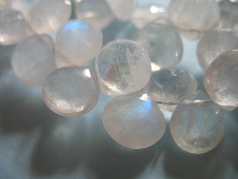 May include: A strand of iridescent moonstone beads, each bead is a light, milky white with a subtle shimmer.