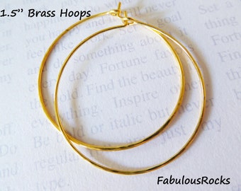 Puede incluir: Dos pendientes de aro de latón dorado, cada uno con un diámetro de 3,8 cm. Los aros son simples y elegantes, con un acabado liso y pulido.