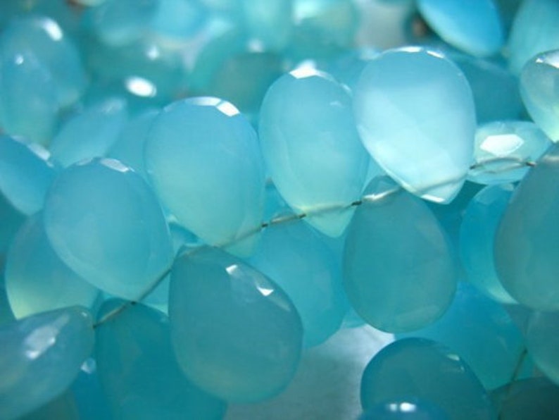 Pu&ograve; includere: Una collana di perle di pietra preziosa blu chiaro, ogni perla ha la forma di una lacrima.