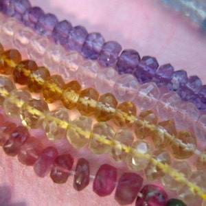 K&ouml;nnte beinhalten: Nahaufnahme einer mehrfarbigen Perlenkette. Die Perlen sind facettiert und haben einen Regenbogen an Farben, darunter Rosa, Gelb, Hellblau und Lila.