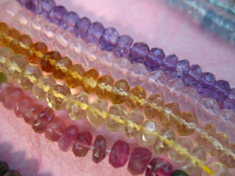K&ouml;nnte beinhalten: Nahaufnahme einer mehrfarbigen Perlenkette. Die Perlen sind facettiert und haben einen Regenbogen an Farben, darunter Rosa, Gelb, Hellblau und Lila.