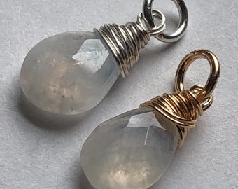 Puede incluir: Dos colgantes de piedra lunar en forma de lágrima, uno con un envoltorio de alambre plateado y un anillo de salto plateado, el otro con un envoltorio de alambre dorado y un anillo de salto dorado.