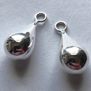 Puede incluir: Dos abalorios de plata en forma de lágrima con un bucle en la parte superior para sujetarlos a joyas.