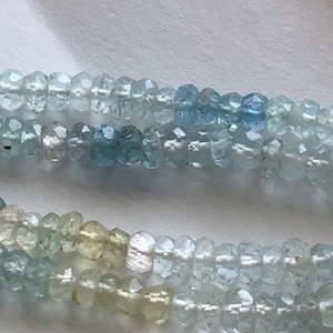 Puede incluir: Una hebra de cuentas de aguamarina azul claro con un degradado de color de azul claro a azul oscuro.