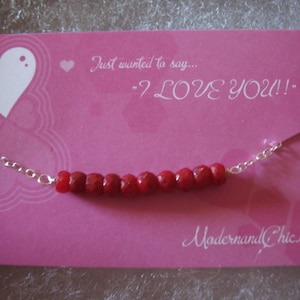 Puede incluir: Una tarjeta rosa con un coraz&oacute;n blanco y el texto "Just wanted to say... "I LOVE YOU!"  Una cadena plateada con cuentas rojas est&aacute; encima de la tarjeta. El texto "ModernandChic.etsy.com" est&aacute; en la parte inferior de la tarjeta.