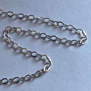 May include: A silver chain necklace with a delicate, oval-shaped link design.
