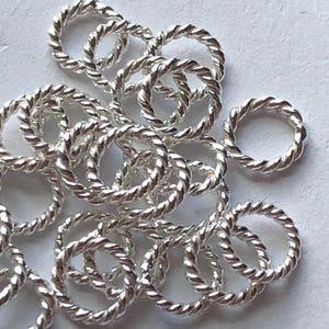 Peut inclure: Un tas de anneaux de saut en argent avec un design de corde torsadée. Les anneaux sont tous de la même taille et sont parfaits pour la fabrication de bijoux.