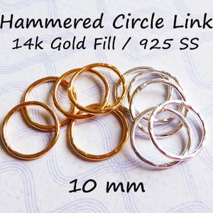 May include: A close-up of 10mm hammered circle links in 14k gold fill and sterling silver. The gold links are stacked on top of each other, while the silver links are spread out.