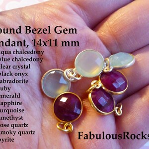 May include: A close-up of five round bezel gem pendants, each measuring 14mm by 11mm. The pendants are made of various gemstones, including aqua chalcedony, blue chalcedony, clear crystal, black onyx, labradorite, ruby, emerald, sapphire, turquoise, amethyst, rose quartz, smoky quartz, and pyrite. The pendants are displayed on a hand, with the text "Fabulous Rocks" visible in the lower right corner.