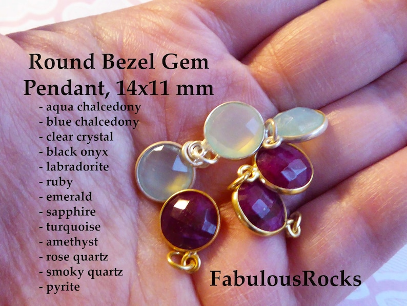 May include: A close-up of five round bezel gem pendants, each measuring 14mm by 11mm. The pendants are made of various gemstones, including aqua chalcedony, blue chalcedony, clear crystal, black onyx, labradorite, ruby, emerald, sapphire, turquoise, amethyst, rose quartz, smoky quartz, and pyrite. The pendants are displayed on a hand, with the text "Fabulous Rocks" visible in the lower right corner.