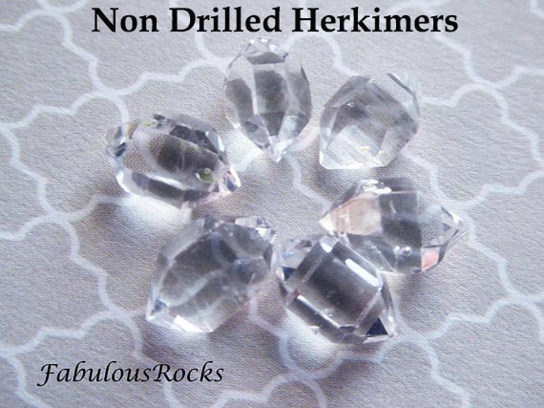 May include: Six clear, undrilled Herkimer diamonds on a white background. The diamonds are all double-terminated and have a natural, rough finish. The text "Non Drilled Herkimers" and "FabulousRocks" is visible in the image.