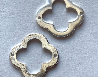 May include: Two silver metal charms in the shape of a four-leaf clover with a hole in each corner.