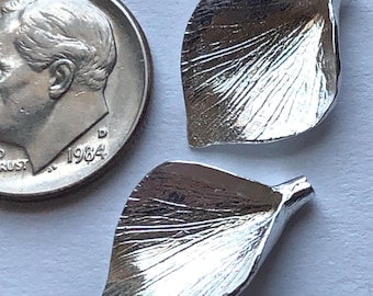May include: Two silver metal leaf-shaped charms with a textured surface. The charms are approximately the size of a US dime.