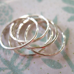 May include: A set of six silver rings, each with a hammered texture, stacked on top of each other.