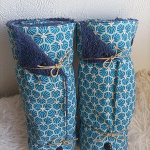 Peut inclure: Deux articles en tissu roulés, à motifs bleu sarcelle et blanc, avec un accent bleu foncé et attachés avec de la ficelle. Le tissu présente un motif géométrique. Les articles sont attachés avec de la ficelle et un bouton foncé.