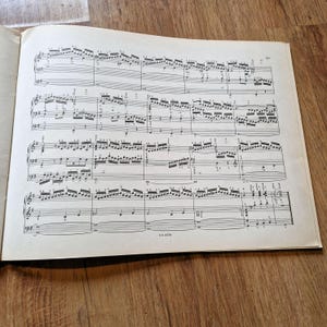 Op de afbeelding: Een zwart-wit bladmuziekboek met gedrukte muzieknoten op de pagina's. Het boek is open op een pagina met een partituur voor een pianostuk. Het paginanummer is 33.