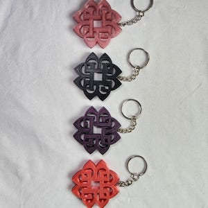 May include: Four keychains with a black and red geometric design. The keychains are attached to silver key rings.