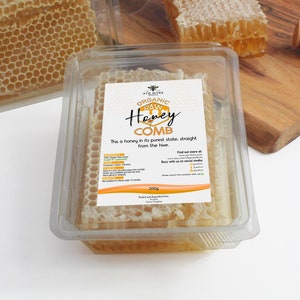 May include: A clear plastic container filled with organic raw honey comb. The honey is a light golden colour and is in a honeycomb shape. The container has a label that says "Organic Raw Honey Comb" and "This is honey in its purest state, straight from the hive." The label also includes the brand name "ATO HIVES" and the weight "200g".
