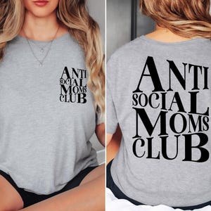 Op de afbeelding: Grijs T-shirt met de tekst "Anti Social Moms Club" in zwart gedrukt op de voor- en achterkant.