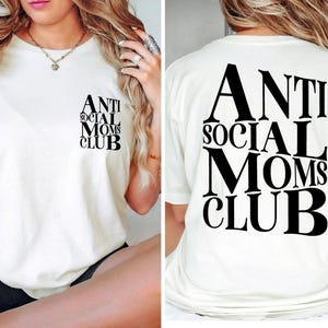Op de afbeelding: Wit T-shirt met zwarte tekst die "Anti Social Moms Club" op de voorkant en achterkant staat.