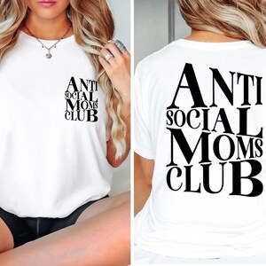 Op de afbeelding: Wit T-shirt met zwarte tekst die "Anti Social Moms Club" op de voorkant en achterkant staat.