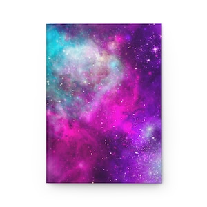 Op de afbeelding: Een notitieboek met een levendig galaxy-ontwerp. De omslag heeft een wervelende mix van turquoise, roze en paarse tinten, bespikkeld met witte sterren. Het notitieboek is rechthoekig en lijkt van een glad materiaal te zijn.