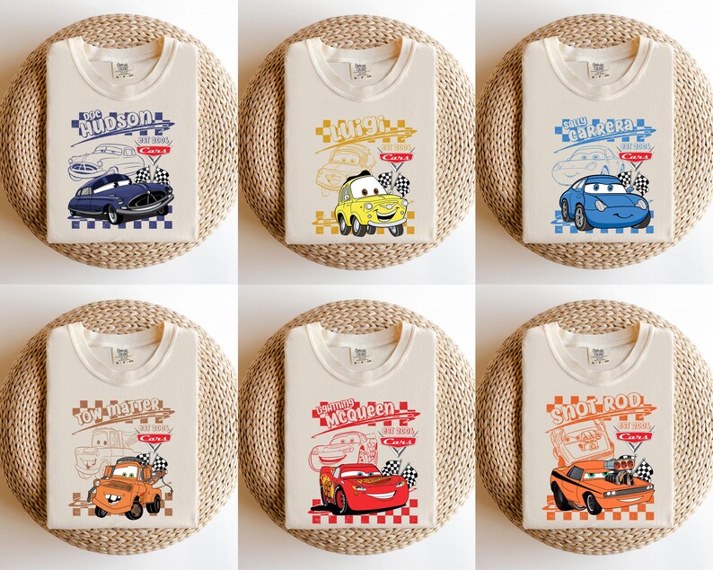 May include: Six beige t-shirts with car graphics. Each shirt displays a different cartoon car design, including names such as "Hudson", "Luigi", "Sally Carrera", "Tow Mater", "McQueen", and "Snot Rod", and checkered flags.