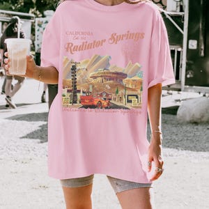 以下が含まれることがあります： 白のセラミックマグカップ、黒いハンドル、手書き風の「But First, Coffee」の文字。 マグカップは白い表面に置かれています。 温かい飲み物用です。