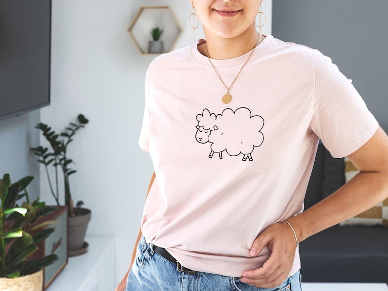May include: A pink t-shirt with a black and white cartoon sheep graphic.