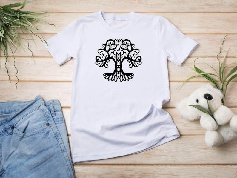 May include: White t-shirt with a black tree of life design. The tree has intricate branches and swirls.
