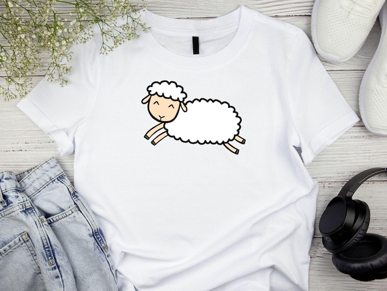 May include: White t-shirt with a cartoon illustration of a white sheep with black eyes and a smile.