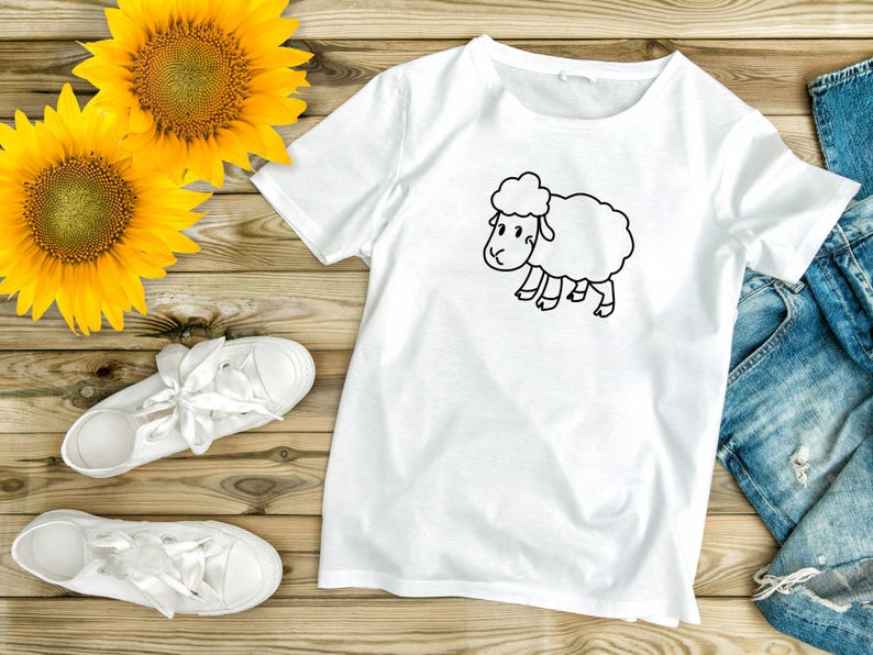 May include: White t-shirt with a black line drawing of a sheep on a wooden background with sunflowers and white sneakers.