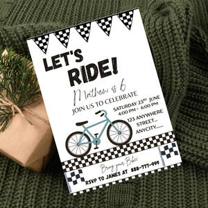 May include: White invitation card with the text "LET'S RIDE!" and a light blue bicycle illustration. The card includes event details and a checkered flag design. A wrapped gift and greenery are in the background.