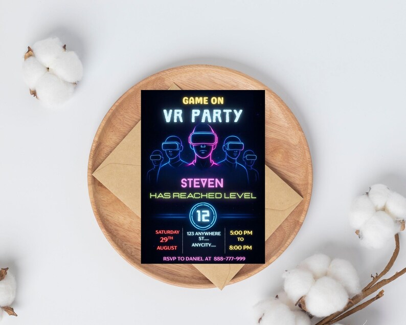 Puede incluir: Una tarjeta de invitaci&oacute;n negra con texto y gr&aacute;ficos en ne&oacute;n azul y rosa para una fiesta de realidad virtual. La tarjeta incluye el texto "GAME ON VR PARTY", "STEVEN HAS REACHED LEVEL" y los detalles del evento. La tarjeta est&aacute; sobre un plato de madera con un sobre.
