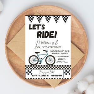 May include: A party invitation with the text "LET'S RIDE!" and "Mathew is 6". The invitation features a light blue bicycle illustration and checkered flag accents. The invitation is on a wooden plate with a brown envelope.