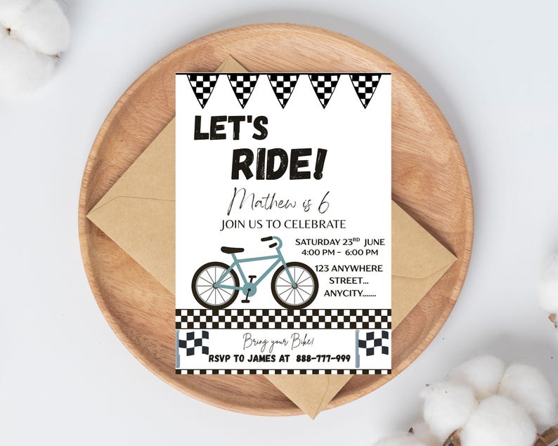 May include: A party invitation with the text "LET'S RIDE!" and "Mathew is 6". The invitation features a light blue bicycle illustration and checkered flag accents. The invitation is on a wooden plate with a brown envelope.
