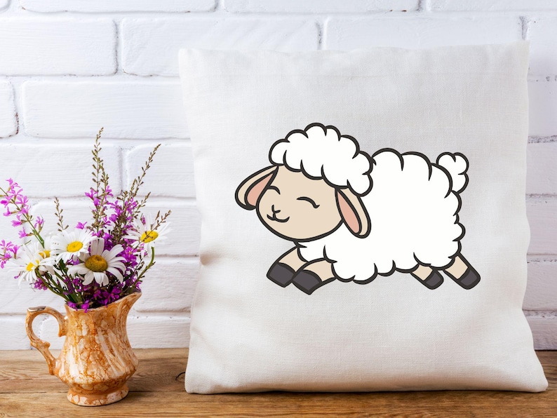 May include: White pillow with a cartoon illustration of a white sheep with black hooves and a pink nose. The sheep is smiling and has its tongue sticking out.
