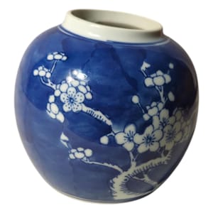 May include: A blue and white porcelain jar with a floral design. The jar is round and has a wide mouth. The floral design is of white blossoms on a blue background.