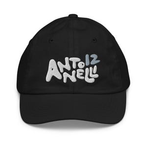 Pode incluir: Um boné de beisebol preto com texto bordado em branco que diz ANTO NELL e o número 12 em azul claro. O boné tem uma copa estruturada, aba curva e um botão no topo, exibindo um design limpo com letras em relevo e bem definidas.